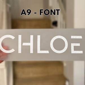 May include: A rectangular, semi-transparent transfer sheet featuring the white text CHLOE in a modern, sans-serif font. The letters have a subtle, speckled texture. Above the sheet, the text A9 - FONT is displayed in black against a blurred background.