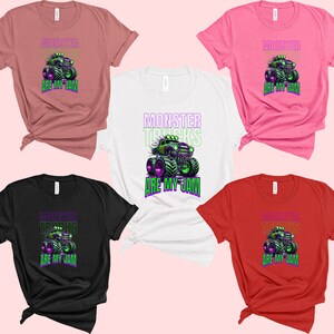 May include: Five t-shirts in different colours with a graphic of a green monster truck with the text "Monster Trucks Are My Jam" in purple and green letters.