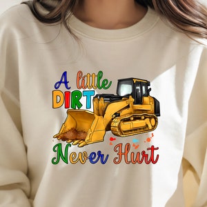 May include: A white sweatshirt with a yellow excavator and the text "A little dirt never hurt" in rainbow colors.