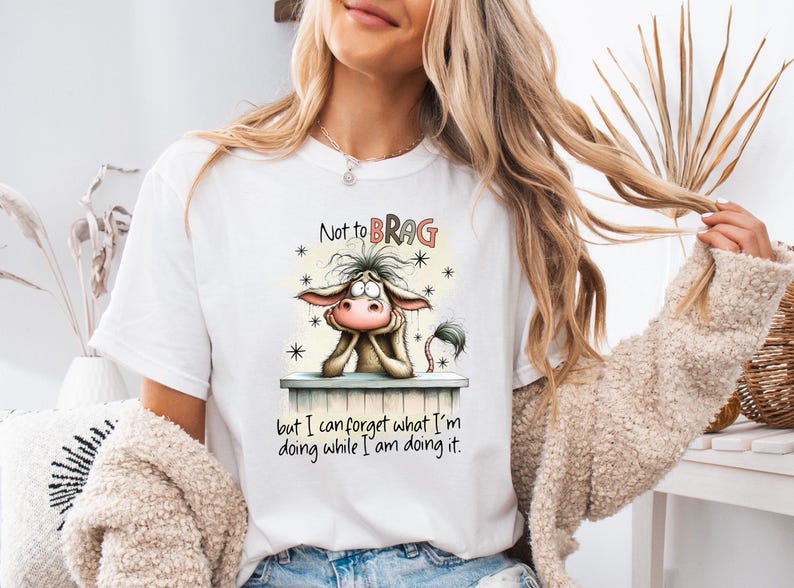 May include: White t-shirt featuring a cartoon donkey with the text "Not to BRAG" above the donkey and "but I can forget what I'm doing while I am doing it" below. The donkey is brown, with a pink nose and ears.