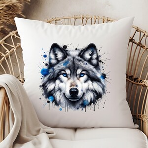 May include: A white throw pillow with a watercolor design of a wolf's face. The wolf has blue eyes and the design is surrounded by blue and black watercolor splatters.