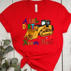 May include: Red t-shirt with a yellow construction vehicle and the text "A little dirt never hurt" in rainbow colors.