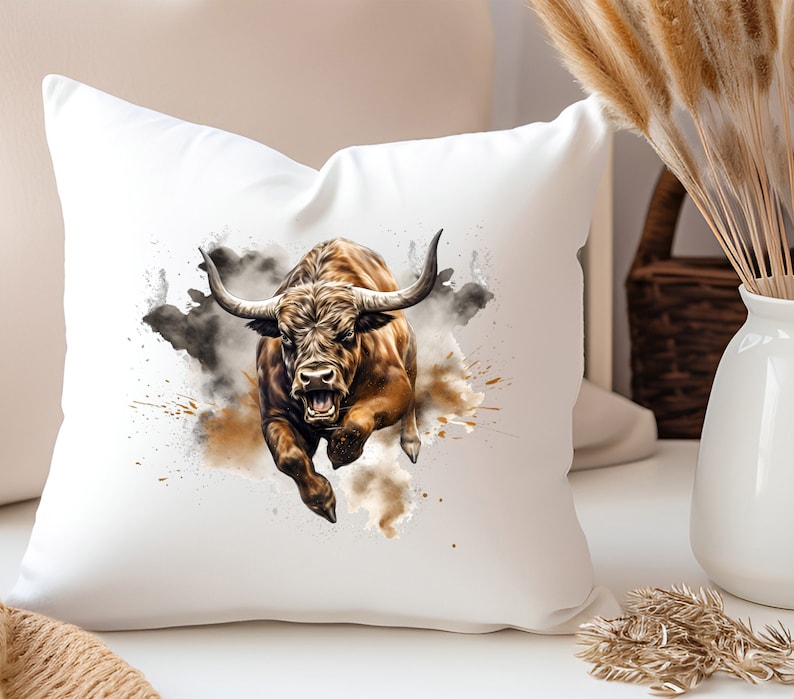 May include: A white throw pillow with a brown and white bull charging through a cloud of brown and gray watercolor paint splatters.