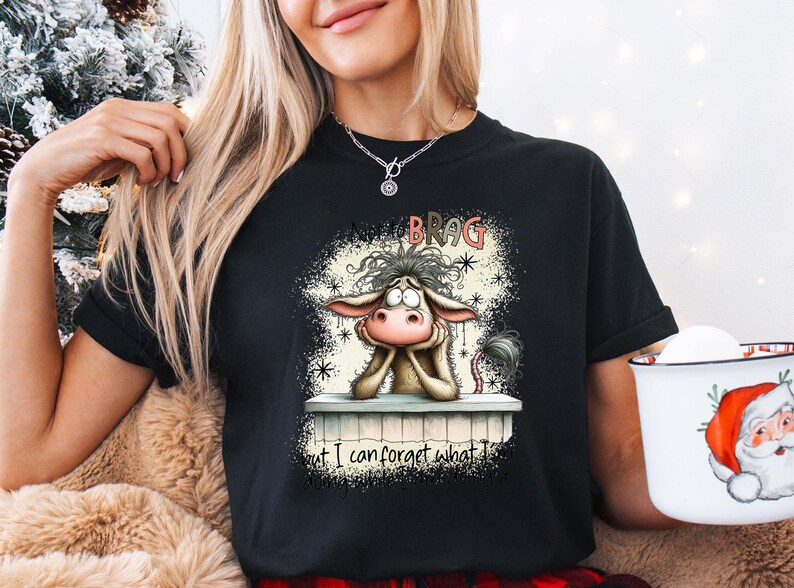 May include: Black t-shirt featuring a cartoon donkey with the text "Not to Brag but I can forget what I..." The donkey is resting its head on its hands. The shirt is a crew neck.