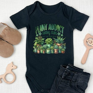 May include: Black baby growsuit with a green and white graphic of potted plants and the text "Plant Addict Social Club Just One More Plant".