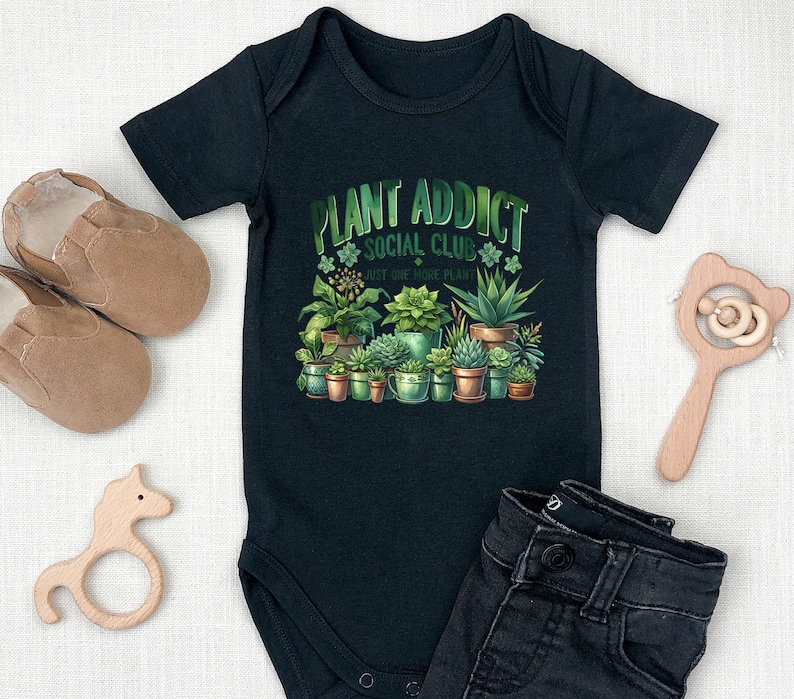 May include: Black baby growsuit with a green and white graphic of potted plants and the text "Plant Addict Social Club Just One More Plant".