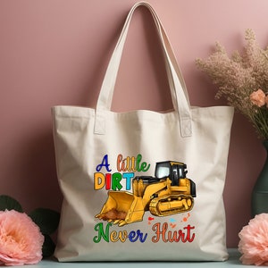 May include: A white canvas tote bag with a yellow bulldozer graphic and the text "A little dirt never hurt" in rainbow colors.