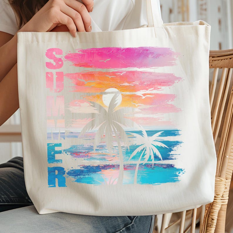 A person is holding a white tote bag with a colorful graphic design depicting a sunset and palm trees.
