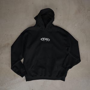 May include: Black hooded sweatshirt with a front pocket and a white, stylized text design on the chest. The hoodie has a drawstring hood and long sleeves. The sweatshirt is made of a soft material.