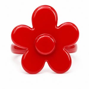 May include: A bright red ring featuring a large, five-petaled flower design. The flower has a smooth, glossy finish with a prominent circular centre and rounded petals. The band of the ring is also red and matches the flower's vibrant colour.