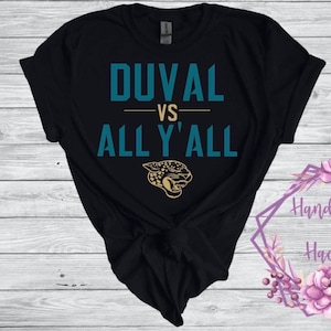 May include: Black t-shirt with teal text that reads "DUVAL VS ALL Y'ALL" and a gold jaguar graphic.