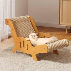May include: A light-coloured wooden cat lounge chair featuring a curved, corrugated cardboard scratching surface. The frame has a natural wood grain finish with vertical cutout slots on the sides, and a white cat is resting on the seat.
