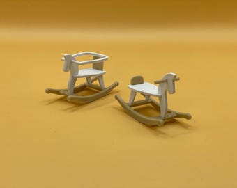 Può includere: Due cavalli a dondolo in legno bianco con dondoli in legno marrone. I cavalli a dondolo sono su una superficie gialla.