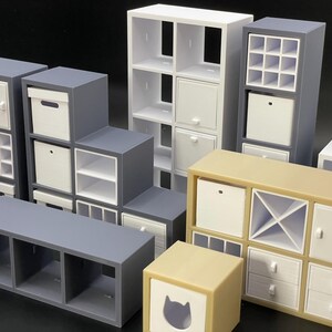 May include: A collection of miniature modular storage units in various colors, including gray, white, and beige. The units feature open shelves, drawers, and cubbies, offering versatile storage solutions.