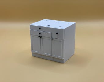 May include: White kitchen cabinet with two drawers and two doors. The cabinet has black knobs and a flat top.