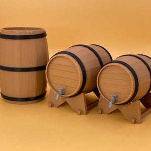 Könnte beinhalten: Drei Holzfässer mit Metallhähnen. Die Fässer sind braun mit schwarzen Metallbändern. Das größte Fass steht aufrecht, während die beiden kleineren Fässer auf Holzständern stehen.