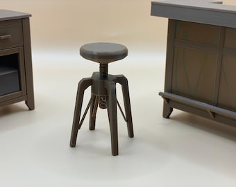 Può includere: Uno sgabello marrone in miniatura regolabile con seduta rotonda e colonna centrale filettata. Lo sgabello ha tre gambe angolate e fa parte di un set di mobili in miniatura. Altri pezzi includono un armadio e un bar.