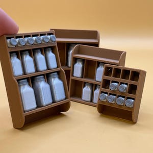 May include: A collection of miniature brown spice racks, each holding small jars with silver lids. The racks are arranged on a yellow surface, showcasing a kitchen or dollhouse theme. The jars appear to be approximately 1 inch in height.