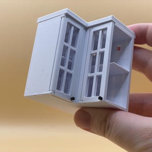 May include: White miniature cabinet with glass doors and shelves. The cabinet is open and the doors are folded back.