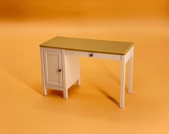 Könnte beinhalten: Ein weißer Schreibtisch mit einer goldenen Tischplatte und einer Schublade. Der Schreibtisch hat links einen Schrank mit einer Tür.