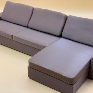 May include: A gray sectional sofa with three cushions and a chaise lounge. The sofa is made of a soft, plush fabric.