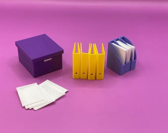 Può includere: Un set di forniture per ufficio: una scatola viola, cartelle gialle, un portadocumenti blu e biglietti bianchi. Gli oggetti sono disposti su uno sfondo viola.