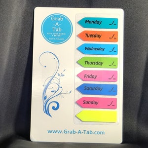May include: A white board with a blue, green, orange, pink, yellow, and light blue arrow shaped sticky notes. The sticky notes have the days of the week written on them. The board also has a blue circle with the text "Grab-A-Tab" and the text "Give your brain a break!" written on it. The board also has the text "www.Grab-A-Tab.com" written on it.