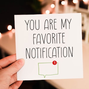 May include: A white card with the text "You are my favourite notification" in black lettering. A green speech bubble with a red notification dot containing the number "1" is below the text.