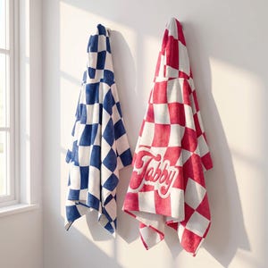 Peut inclure: Deux serviettes à capuche suspendues au mur. L'une présente un motif à carreaux bleu et blanc. L'autre présente un motif à carreaux rouge et blanc avec le mot Tabby brodé dans une police cursive sur la surface avant de la serviette.