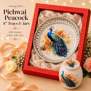 May include: A German Silver 8-inch tray and jar set featuring a peacock design. The tray has a decorative silver border and a central peacock illustration. The matching jar has a lid with a clear knob. Both items are presented in a red box.
