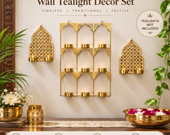 May include: A 3-piece Jharokha wall tealight decor set featuring gold-toned metal frames with intricate lattice patterns. The set includes one large rectangular wall-mounted candle holder and two smaller arched wall-mounted candle holders.