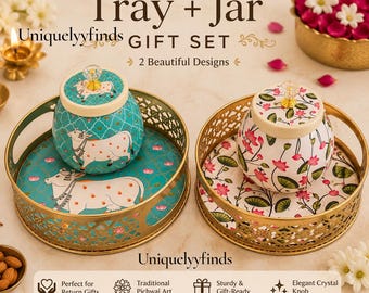 May include: A Tray + Jar GIFT SET featuring two round gold-tone metal trays with lattice sides and two matching lidded jars. One jar and tray set is teal with white cow illustrations, the other is white with pink lotus flower patterns.