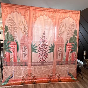 May include: A large rectangular fabric backdrop featuring a printed architectural scene with peach and pink arches, green palm trees, and floral motifs. The design includes a low railing, two peacocks at the base, and a central flowering plant.