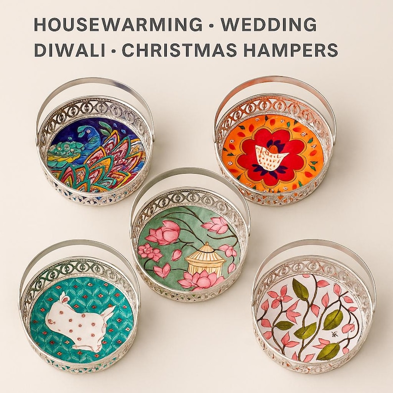 May include: Five round silver-toned metal baskets with handles, each featuring a unique colorful base illustration. The text HOUSEWARMING WEDDING DIWALI CHRISTMAS HAMPERS is printed at the top. The designs include a peacock, a floral pattern, a rabbit, a lotus pond, and a vine.