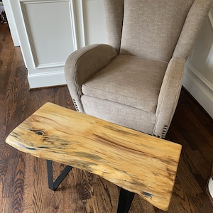 May include: A natural wood live edge coffee table with black metal legs. The table has a rustic, organic look and is perfect for a modern or farmhouse style home.