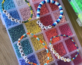 May include: A clear plastic storage box filled with colorful beads and small letter beads. The beads are arranged in rows and columns. The letter beads spell out the names "Alonzo", "Albon", "Norris", and "Sergeant".