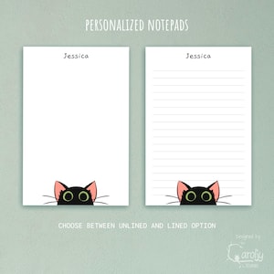 May include: Two white rectangular notepads featuring the name Jessica at the top and a black cat head with large green eyes and pink ears at the bottom. One notepad is blank, while the other contains horizontal lines for writing notes.