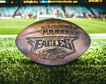 May include: A wooden football with the Philadelphia Eagles logo and the words "Philadelphia Eagles" carved into the side.