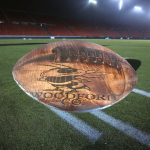 May include: A wooden football with a bee design and the text "WOODFORD CO."