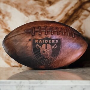 May include: A brown leather football with the word "RAIDERS" and a skull and crossbones logo.