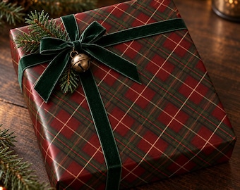 May include: A square gift box wrapped in dark red and green plaid paper, tied with a dark green velvet ribbon. A small metallic jingle bell and a sprig of evergreen needles are tucked into the center of the bow on the top of the package.