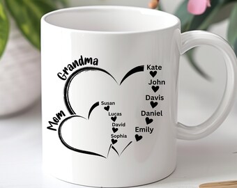 Könnte beinhalten: Weiße Keramiktasse mit einem schwarzen Herzdesign und den Worten "Mom Grandma" sowie den Namen der Familienmitglieder: Kate, John, Davis, Daniel, Emily, Susan, Lucas, David, Sophia.