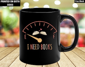 Puede incluir: Taza de cerámica negra de 11 oz con un diseño de indicador que dice "I NEED BOOKS". El indicador muestra un libro abierto y una aguja que apunta a vacío. El texto "PRINTED ON BOTH SIDES" está en la parte superior izquierda.