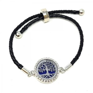 May include: A black leather bracelet with a silver tree of life charm. The charm is surrounded by clear rhinestones and has a blue center.