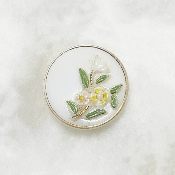 a white glass button with little yellow flowers