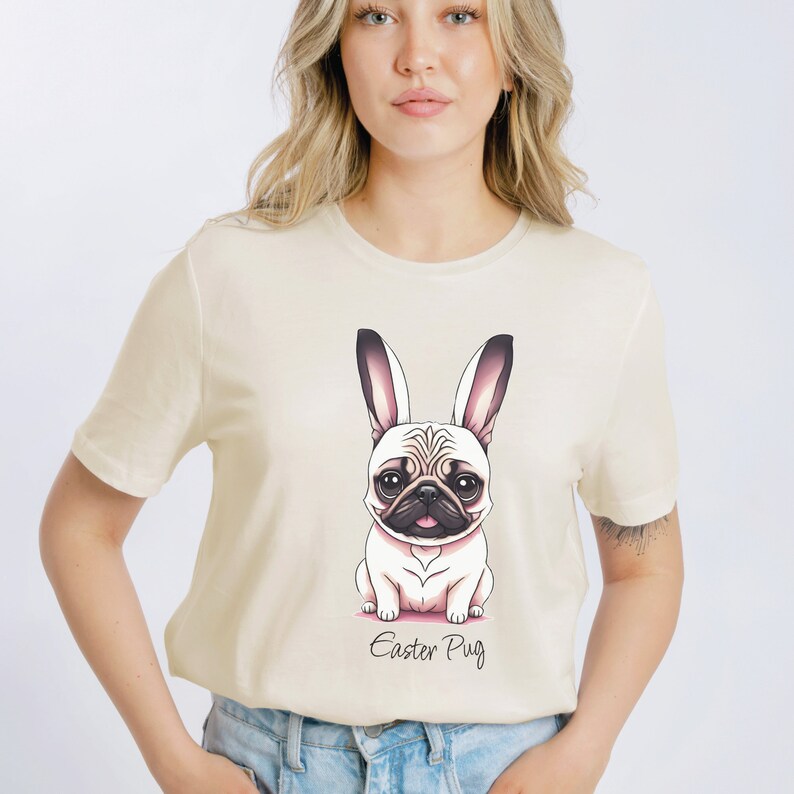 May include: A beige t-shirt featuring a cartoon image of a pug wearing bunny ears. The text "Easter Pug" is printed below the image.
