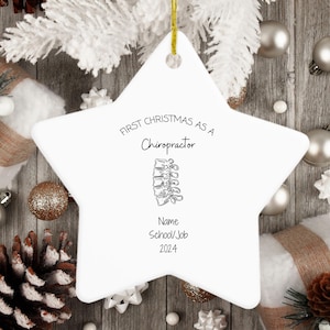 May include: A white star-shaped ceramic ornament featuring black text that reads First Christmas as a Chiropractor, followed by a line drawing of a human spine, with placeholders for Name, School/Job, and the year 2024 printed in black ink.