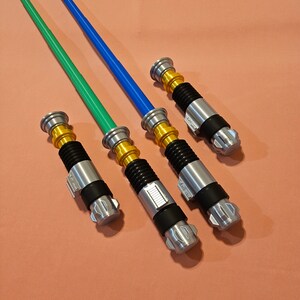 May include: Four lightsaber toys with silver and gold handles and green, blue, and silver blades.
