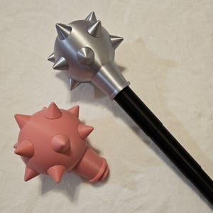 May include: Two spiked maces, one silver and one pink, with black handles. The silver mace is on the right and the pink mace is on the left.