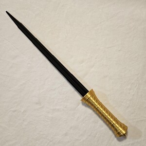 May include: A black metal sword with a gold-colored handle. The handle has a twisted design.